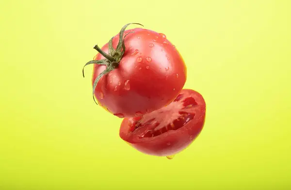 Olgun bir domates sarı arka planda havayı kesiyor. — Stok fotoğraf