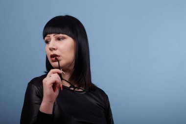 Stüdyoda bir fotoğrafçıya mavi arka planda poz veren gözlüklü güzel bir kızın portresi