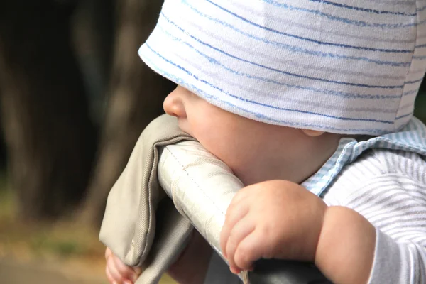 Kleiner Junge beißt in seinen Rollstuhl — Stockfoto