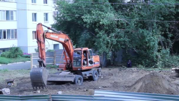 Turuncu kazıcı bir inşaatta çalışan — Stok video
