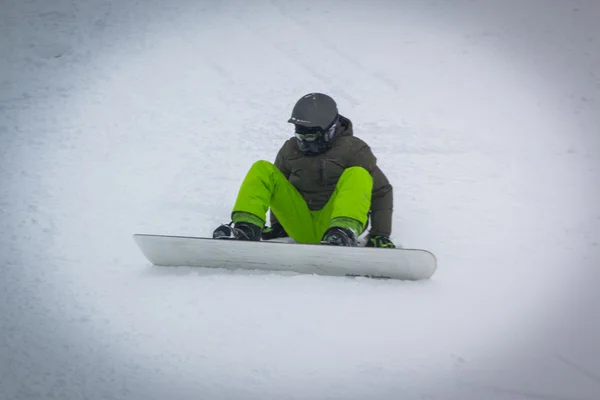 Snowboarder συρόμενη κάτω από μια κλίση σε μια ηλιόλουστη ημέρα — Φωτογραφία Αρχείου