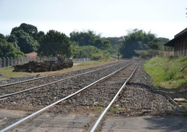 Demiryolu. Brezilya 'nın iç kesimlerinde demiryolu, kargo ve ürünleri panoramik görüntüde taşımak için kullanılır demiryolu yanında ahşap kütükler ve mavi gökyüzü, ağaçlar ve Brezilya' da çimenlik, Güney Amerika 'da eğri bir arka plan