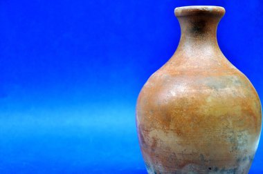 Esmer ot. Batı Afrika sürahisi, ilkel konteynır, zaman aşımına uğramış, mavi arka planda fotoğrafı var.