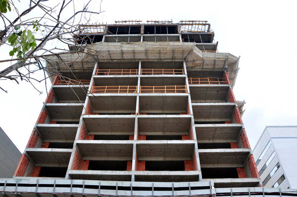 Facade of a building under construction, with protective timber in a panoramic view from the bottom up, with the sky in the background and green trees on the side, Brazil, South America 