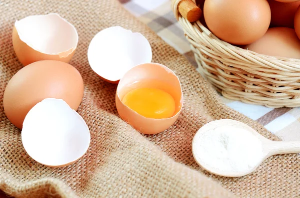 Wicker basket with eggs and raw egg on a linen tablecloth Royalty Free Stock Images