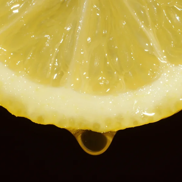 Une tranche de citron avec une goutte d'eau sur un fond noir — Photo