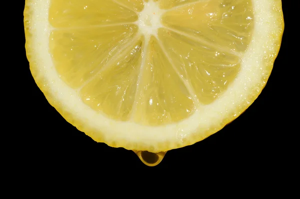 Une tranche de citron avec une goutte d'eau sur un fond noir — Photo