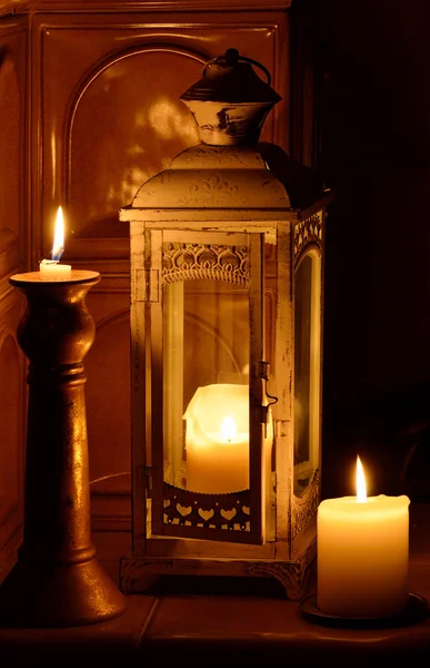 Still life with candles and decorative lantern at an ancient tiled stove — Stock Photo, Image