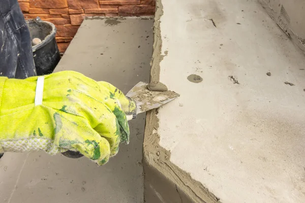 Mans mano en guantes de trabajo nivelando la superficie de un paso antes de la colocación de pavimentación. El hombre limpia el pegamento de mampostería con una espátula — Foto de Stock