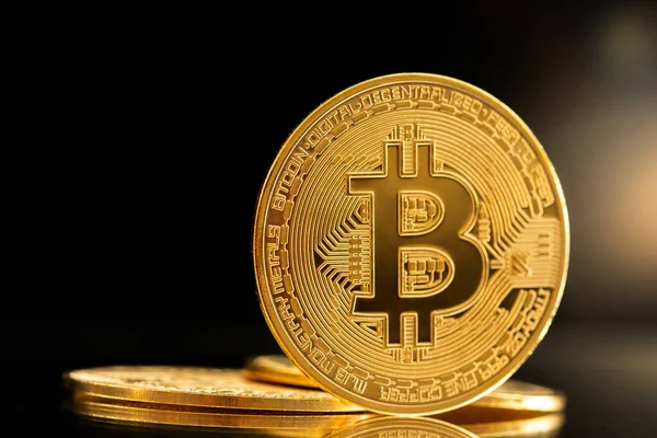 Gouden Bitcoin munt met reflectie en glans. Geïsoleerd op zwarte achtergrond. Stockfoto