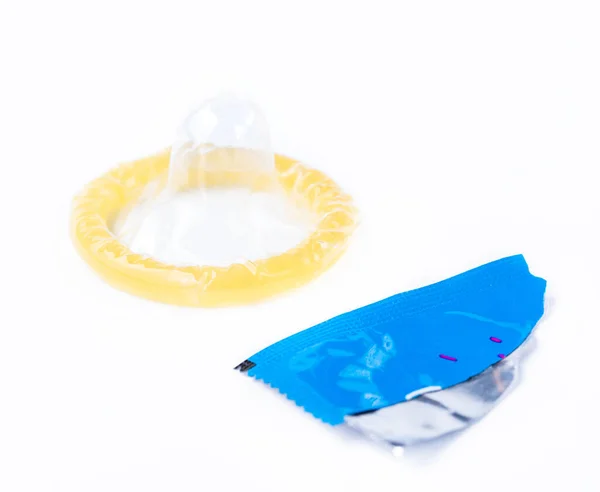 Unrolled condom and piece of wrapper isolated on white background. — Stock Photo, Image
