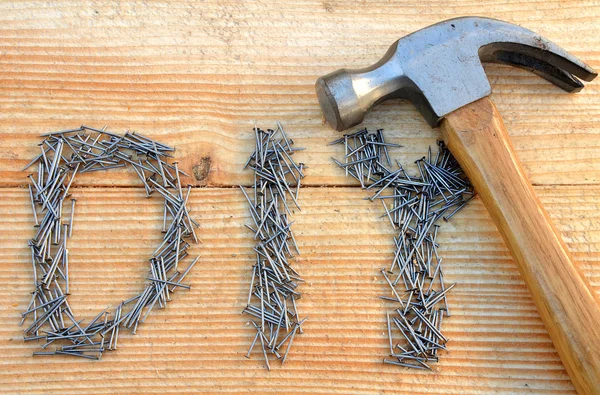 DIY (do it yourself) text from small nails and hammer — Stock Photo, Image