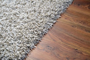 White shaggy carpet on brown wooden floor clipart