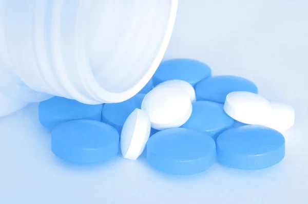 Bottle of pour out blue pills of drugs — Stock Photo, Image