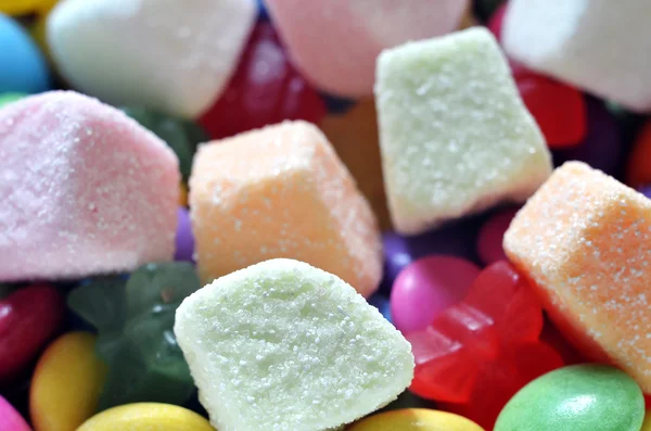 Zure gelei roze, oranje en witte suikergoed op gekleurde smarties — Stockfoto