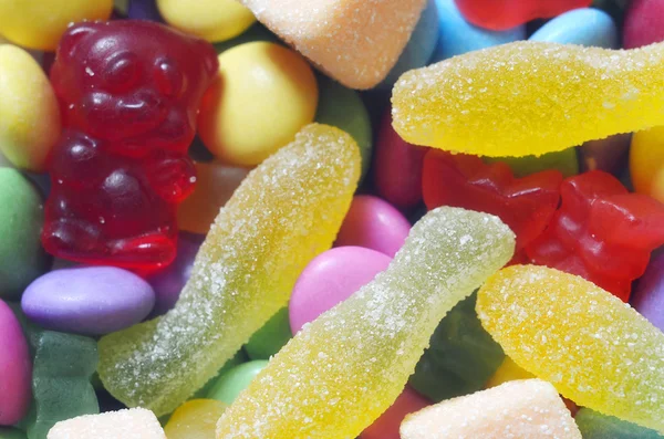 Syrlig gelé rosa fisk, orange och vitt godis på färgade smarties — Stockfoto