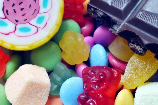 Lollipop, ositos de goma, chocolate y caramelos agrios en smarties de colores —  Fotos de Stock