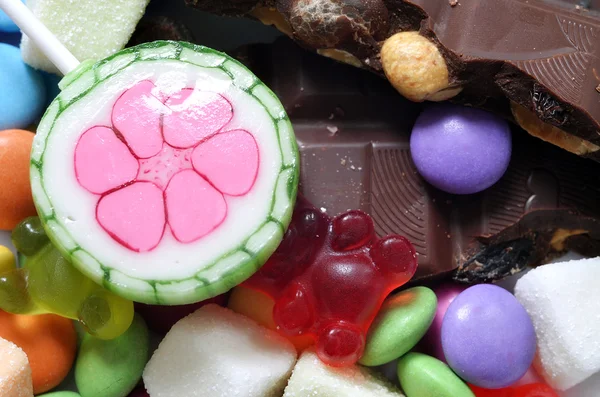 Lolipop, şeker, çikolata ve ekşi şeker renkli smarties üzerinde — Stok fotoğraf