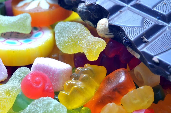 Sucette, ours gommeux, chocolat et bonbons acidulés sur smarties colorées — Photo