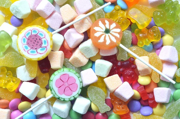 Candy, lízátko, barevné lentilky a pozadí gumoví medvídci — Stock fotografie