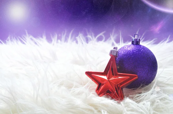 Purple christmas ball and red star lying on a white furry nest — Stock Photo, Image