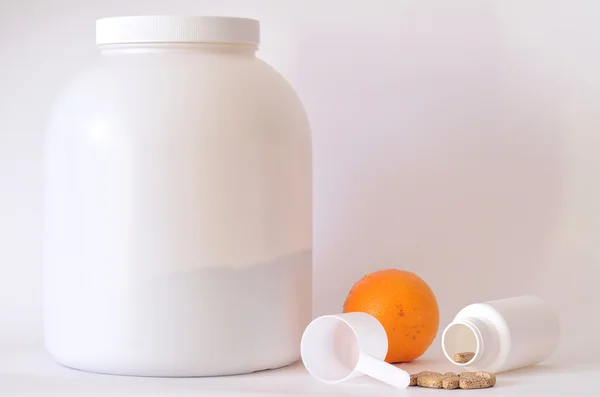 Gran frasco de proteína en polvo, botella de pastillas, naranja y cucharada —  Fotos de Stock