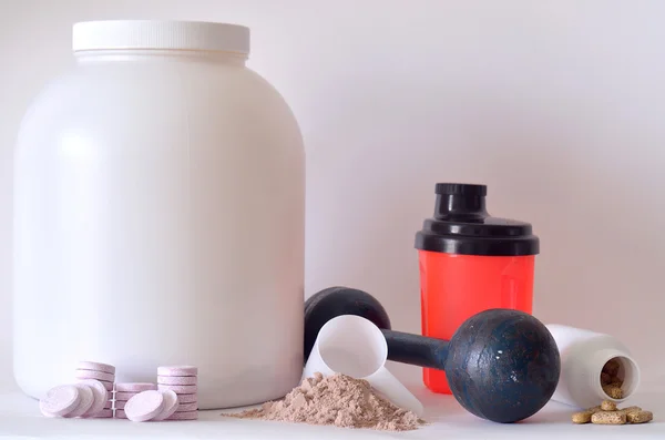 Grande barattolo di proteine in polvere, manubri, shaker, pillole e compresse — Foto Stock