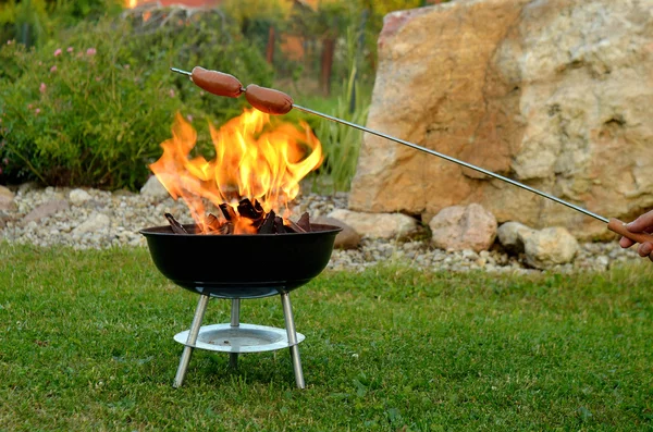 Asar salchichas sobre un fuego — Foto de Stock