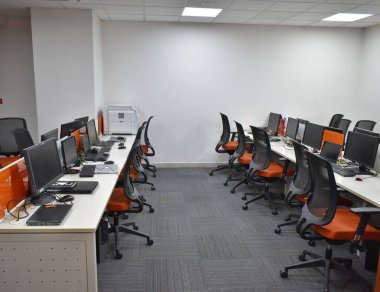 Beyaz duvarları, beton zemini ve sıra sıra siyah bilgisayar masaları olan modern açık uzay ofisinin en üst görüntüsü. Pazarlama şirketi konsepti