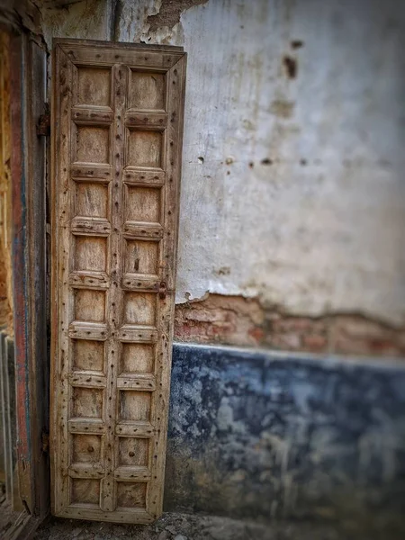 Vintage old warehouse wooden brown painted door with ancient brick wall of limestone. Front view of gates to abandoned warehouse in india