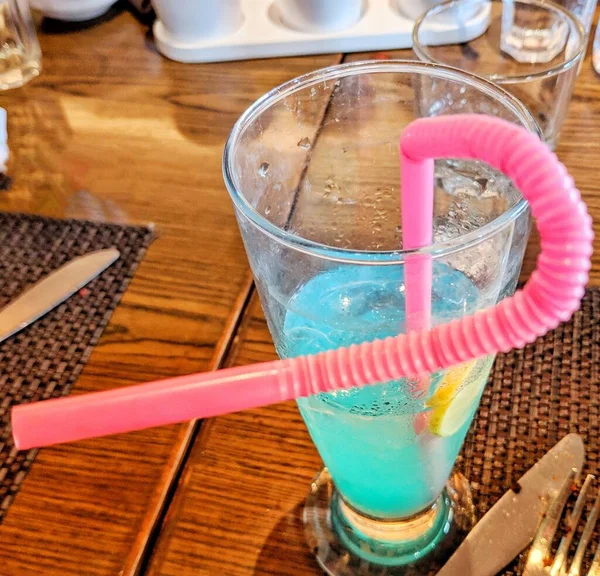 氷とレモンと新鮮な青のカクテル 藁と氷のキューブと新鮮な夏のカクテル 黒を基調としたストロベリーソーダのグラス — ストック写真