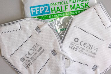 Neckargemund, Almanya: 4 Mart 2021: İki FFP-2 maskesi ve aerosollere karşı koruma amaçlı ambalaj. Gri zemin üzerinde CE test mührü bulunan korona virüslerine karşı
