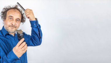 Kötü saçlı komik görünüşlü bir adam karar tarağıyla yüzleşiyor ya da saç kesme makinesiyle kesiliyor. Boşluğu sağa kopyala