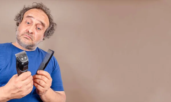 man with bad hair day facing decision comb or cut with hair trimmer. copy space to the right