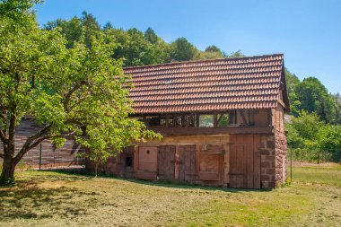 Güney Almanya 'da bir ormanın kenarındaki bir çayırda eski bir tarım binası.
