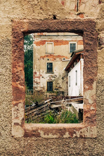 old abandoned and run down factory building photographed through a sandstone window frame without window