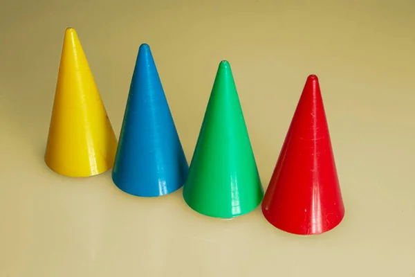 Vier Unterschiedlich Farbige Kegelförmige Spielsteine Einer Reihe Vor Ockergelbem Hintergrund — Stockfoto
