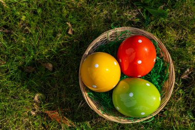 Çayırdaki sepette renkli paskalya yumurtaları.