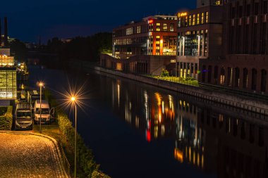 Berlin, Almanya - 27 Temmuz 2018: Berlin-Tempelhof 'taki Teltow Kanalı üzerinde eski depoları olan bir limanın gece çekimi. Renkli ışıkları olan restoranlar da var..
