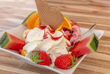 Sığ bir kase lezzetli dondurmanın, mevsimlik meyvelerin, çırpılmış kremanın ve waffle 'ın yakın çekimi..