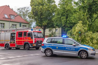 Berlin, Almanya - 12 Haziran 2019: Şiddetli bir fırtınadan sonra Almanya 'nın başkenti Berlin' de bulunan köklerinden sökülmüş bir ağaç. Polis caddeyi temizliyor..