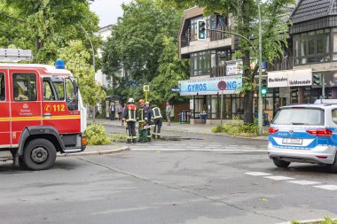 Berlin, Almanya - 12 Haziran 2019: Şiddetli bir fırtınadan sonra Almanya 'nın başkenti Berlin' de bulunan köklerinden sökülmüş bir ağaç. Polis caddeyi temizliyor..