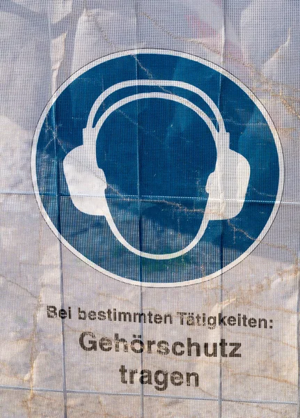 透明防水油布上的符号作为建筑工地安全的标志 你可以看到你应该戴上耳罩 德文的意思是 戴上耳罩 — 图库照片