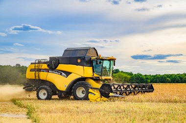Berlin, Almanya - 05 Temmuz 2019: Berlin yakınlarında bulutlu bir gökyüzünün altında hareket eden bir hasatçının yan görüntüsü.