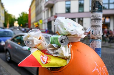 Berlin, Almanya - 28 Haziran 2019: Bir sokak festivali yüzünden yol kenarında aşırı dolu bir çöp kutusu duruyor.