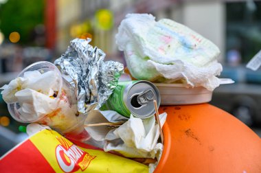 Berlin, Almanya - 28 Haziran 2019: Bir sokak festivali yüzünden yol kenarında aşırı dolu bir çöp kutusu duruyor.