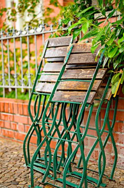 Yağmurlu bir günde çitlere yaslanan katlanır bahçe sandalyeleri.