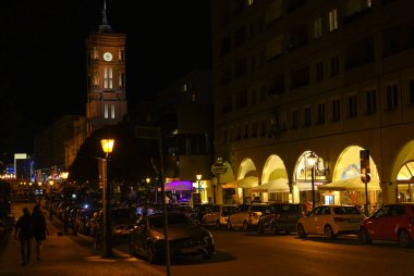 Berlin, Almanya - 3 Ağustos 2019: Berlin 'in merkezindeki Kızıl Kasaba Salonunun görüntüsü. Ön planda aydınlatılmış restoranları olan küçük bir cadde görüyorsunuz..