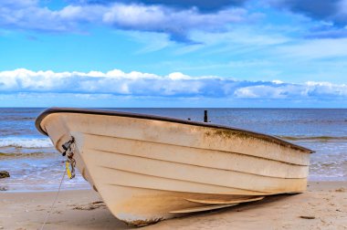 Issız bir tekne kumsalda uzanıyor. Adanın kıyılarında. Kullanım alanı, Almanya, mavi ve bulutlu bir gökyüzünün altında..