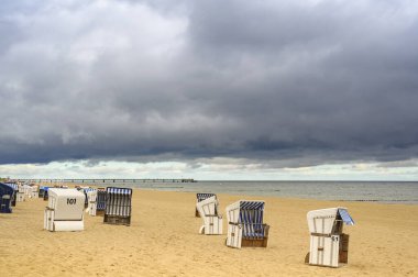 Plajda plaj sandalyeleri ve deniz manzaralı dramatik fırtına bulutları..